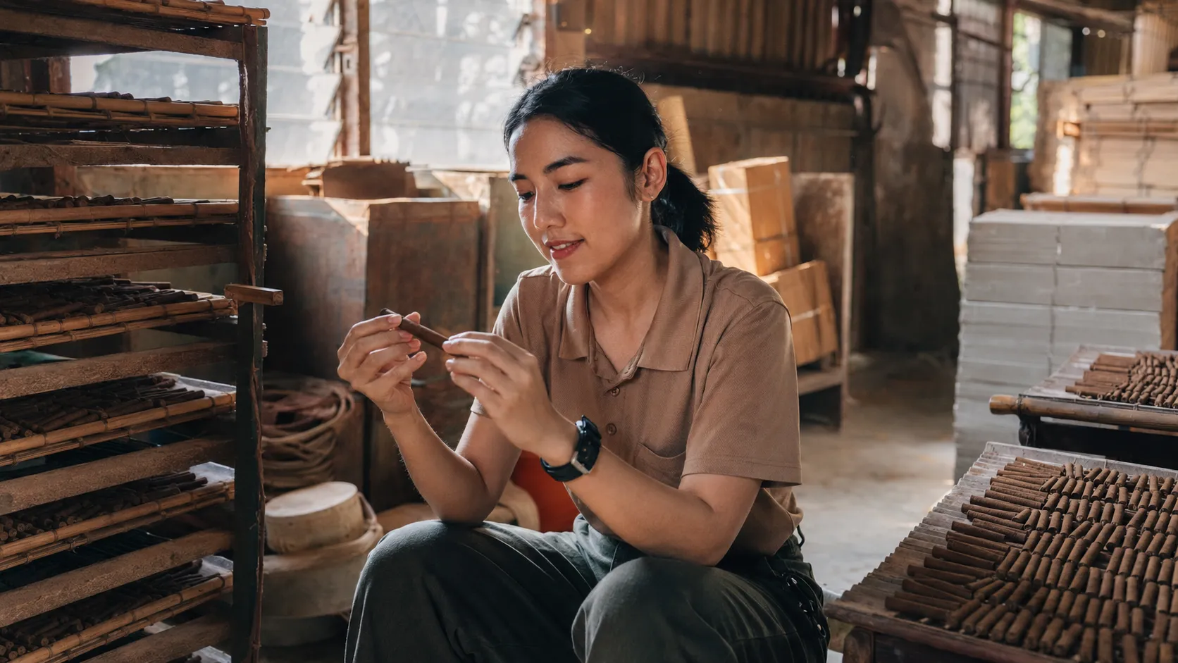 Vanessa holding a stick of cigar incense on the floor of her family's incense factory in Ipoh