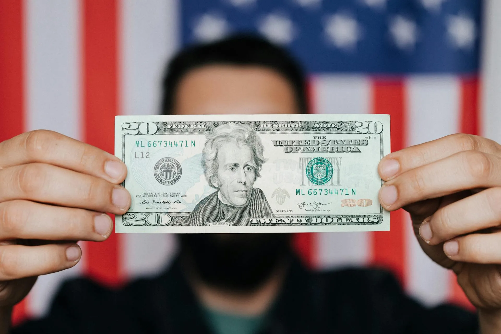 A man holds up a 20 US Dollar note