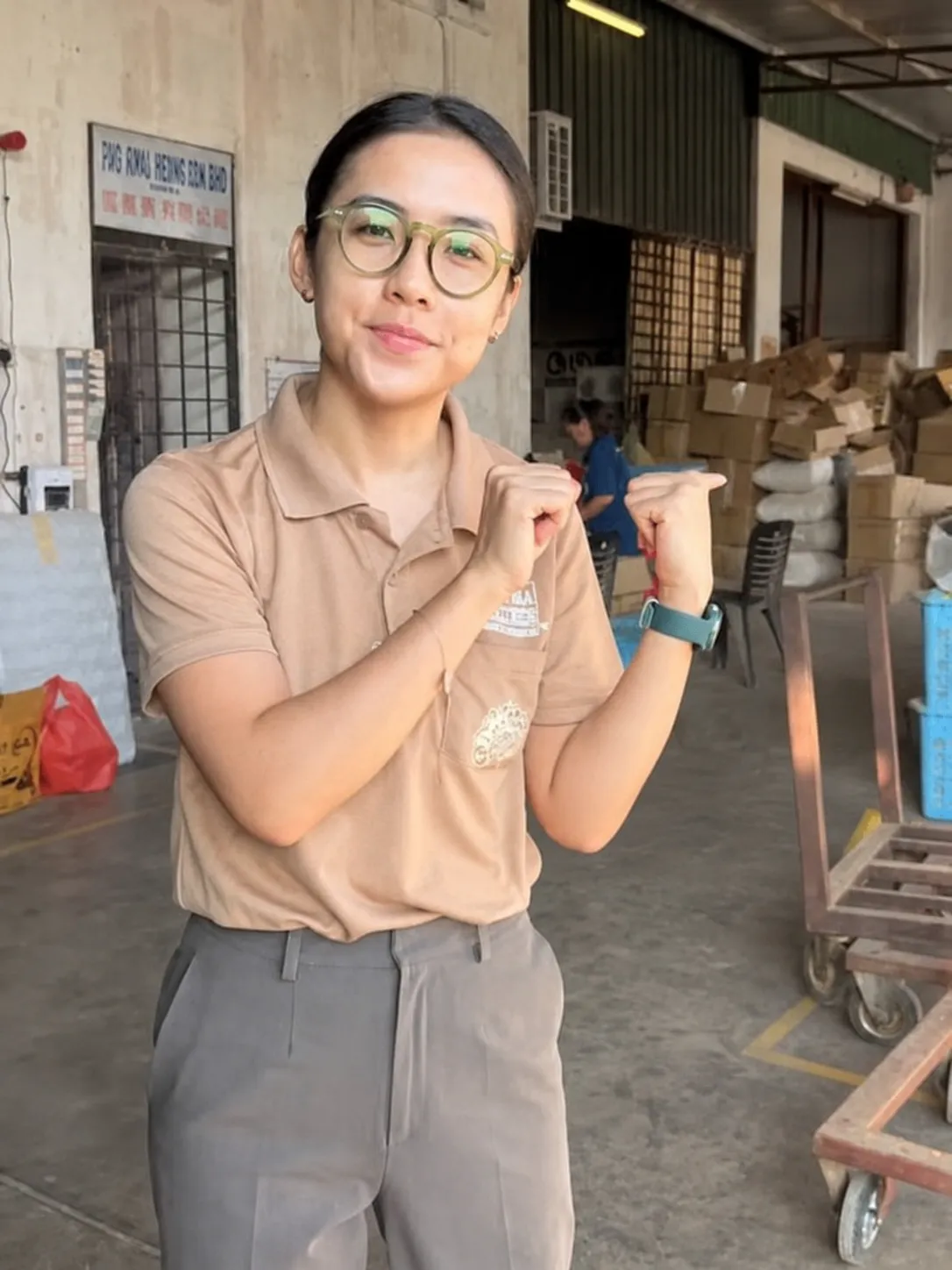 Vanessa presenting a product to camera on the floor of her family's incense factory in Ipoh