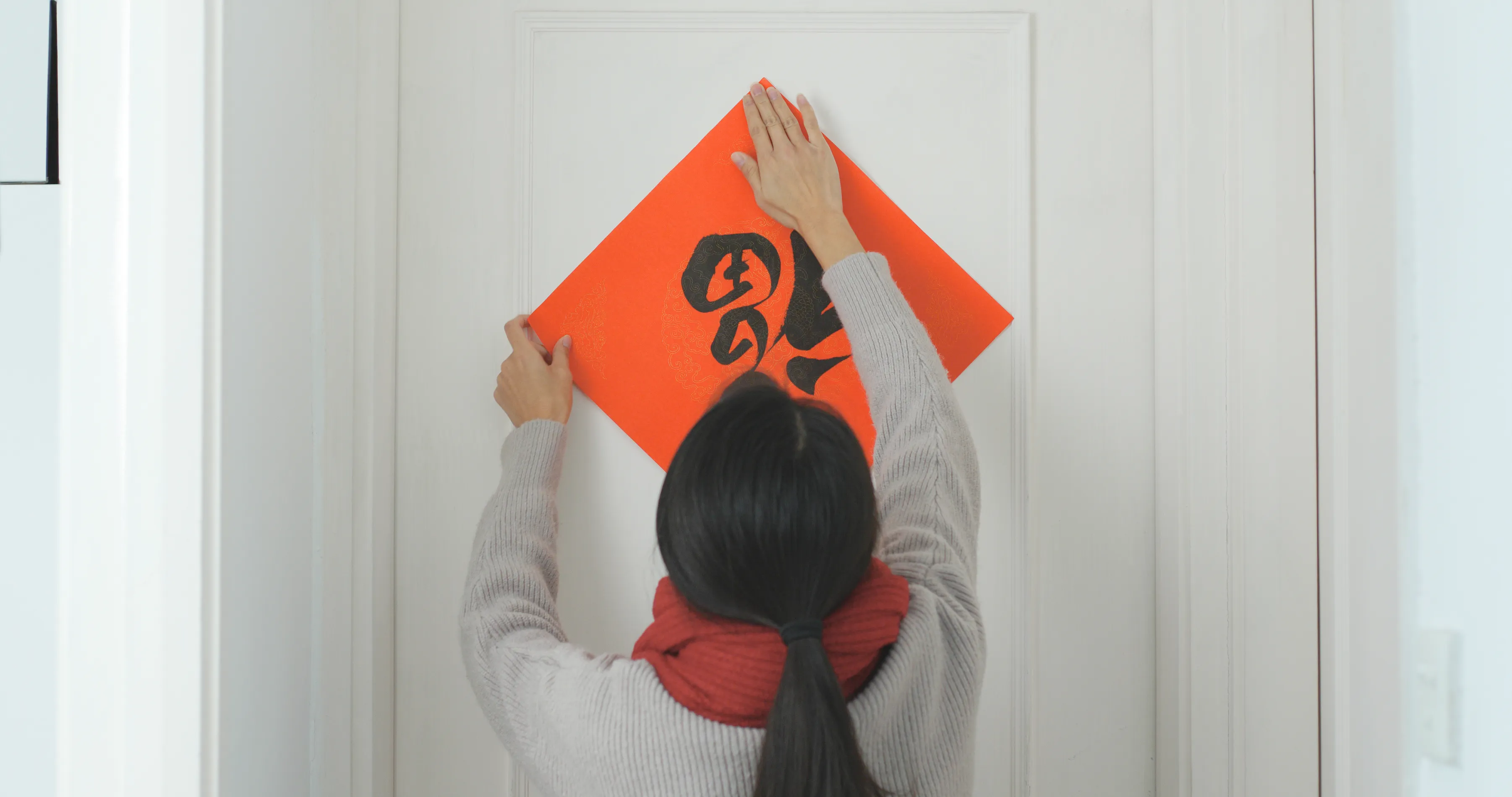 A woman hanging a decoration on a door