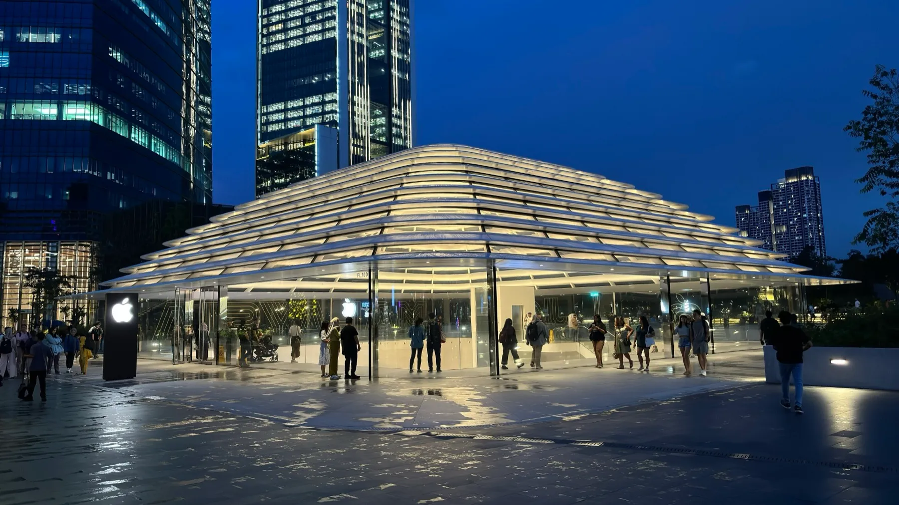 The Apple store at The Exchange TRX in Kuala Lumpur, lit up at dusk with shoppers outside