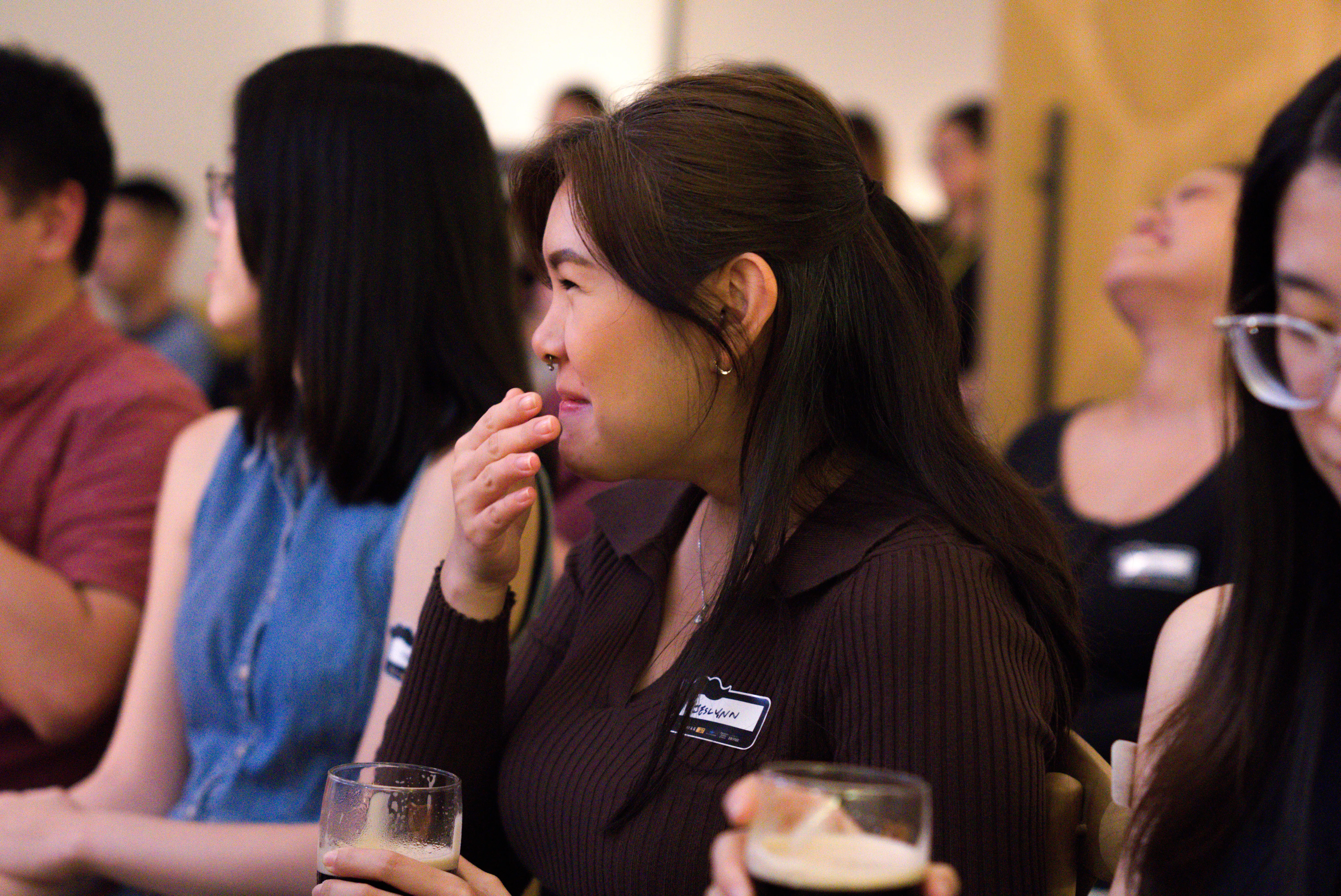 A girl containing her laughter with a pint of Guinness in her hands.