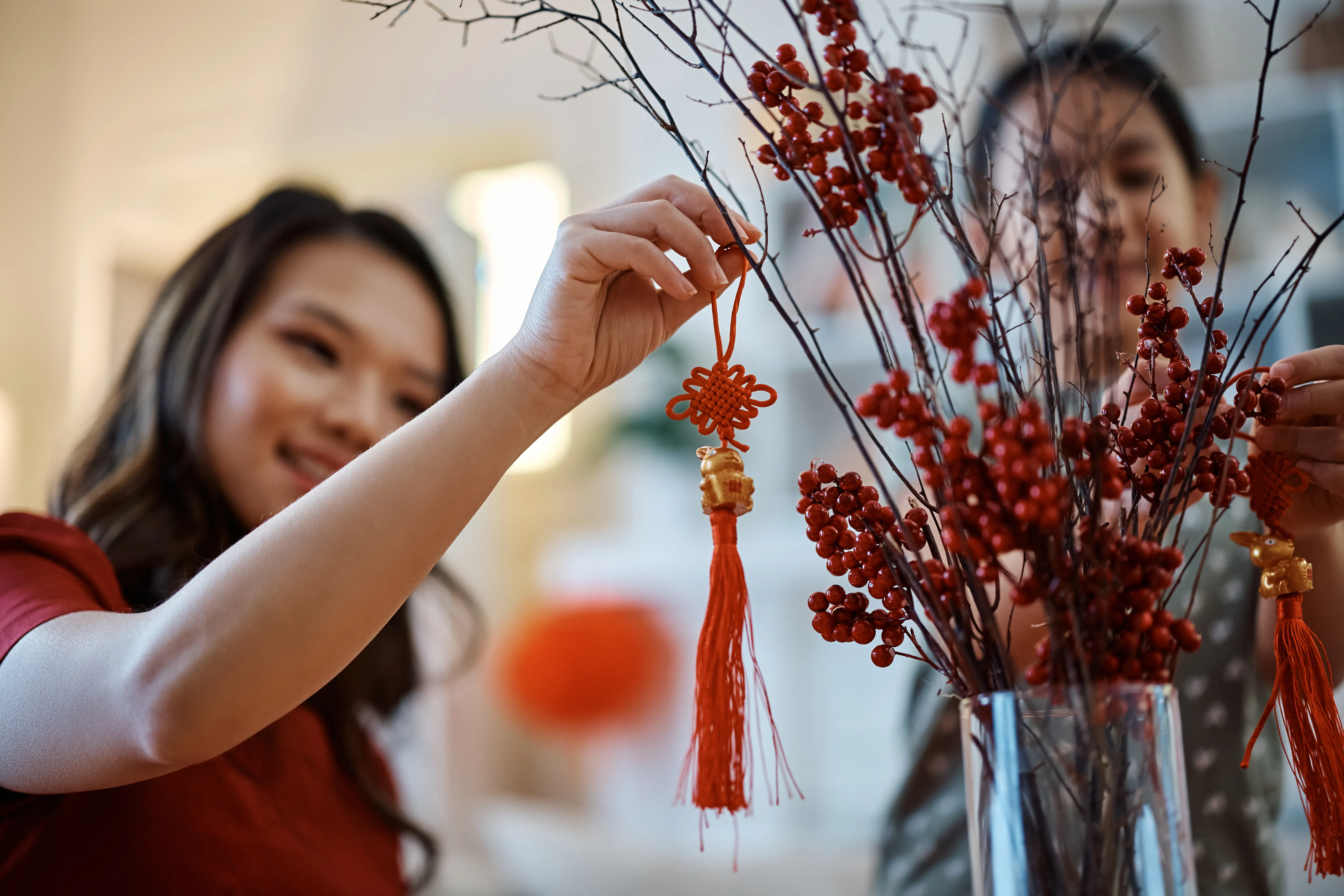 A woman hanging a chime on fake flowers