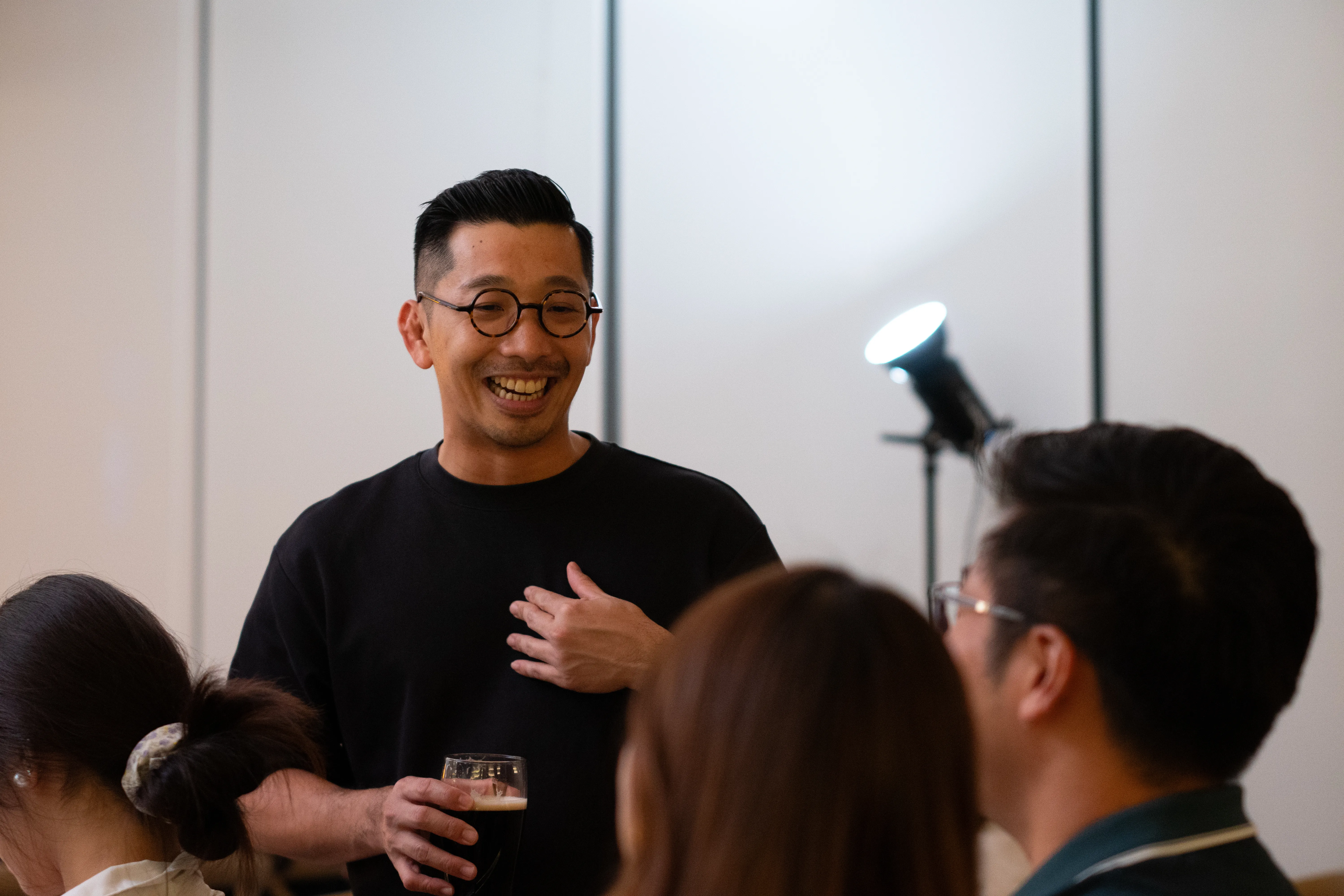 A man smiling while interacting with audience and holding a beer