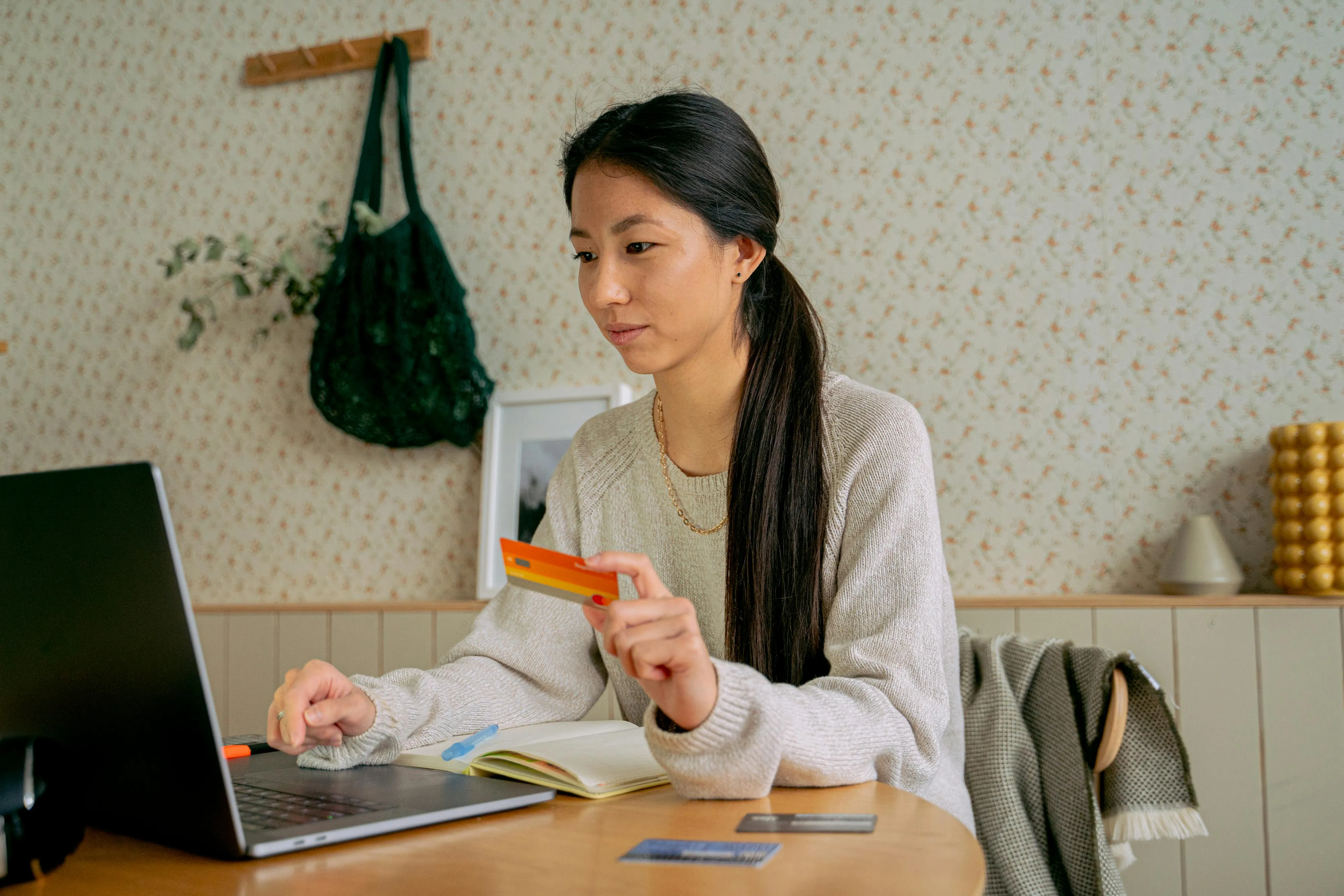 An asian woman holds credit card while doing online shopping